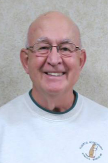 Bob Pedigo smiles at the camera while wearing a Flickertail Woodcarvers sweatshirt